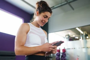 Woman checking her free workout app during a workout session at the gym